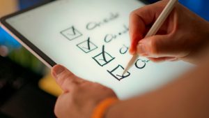 A hand ticking items off a checklist on a tablet